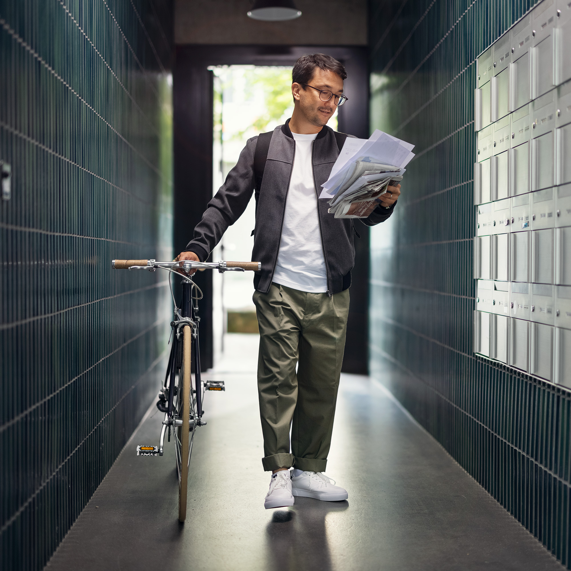Mann steht mit dem Fahrrad vor den Briefkästen im Eingang eines Wohnhauses